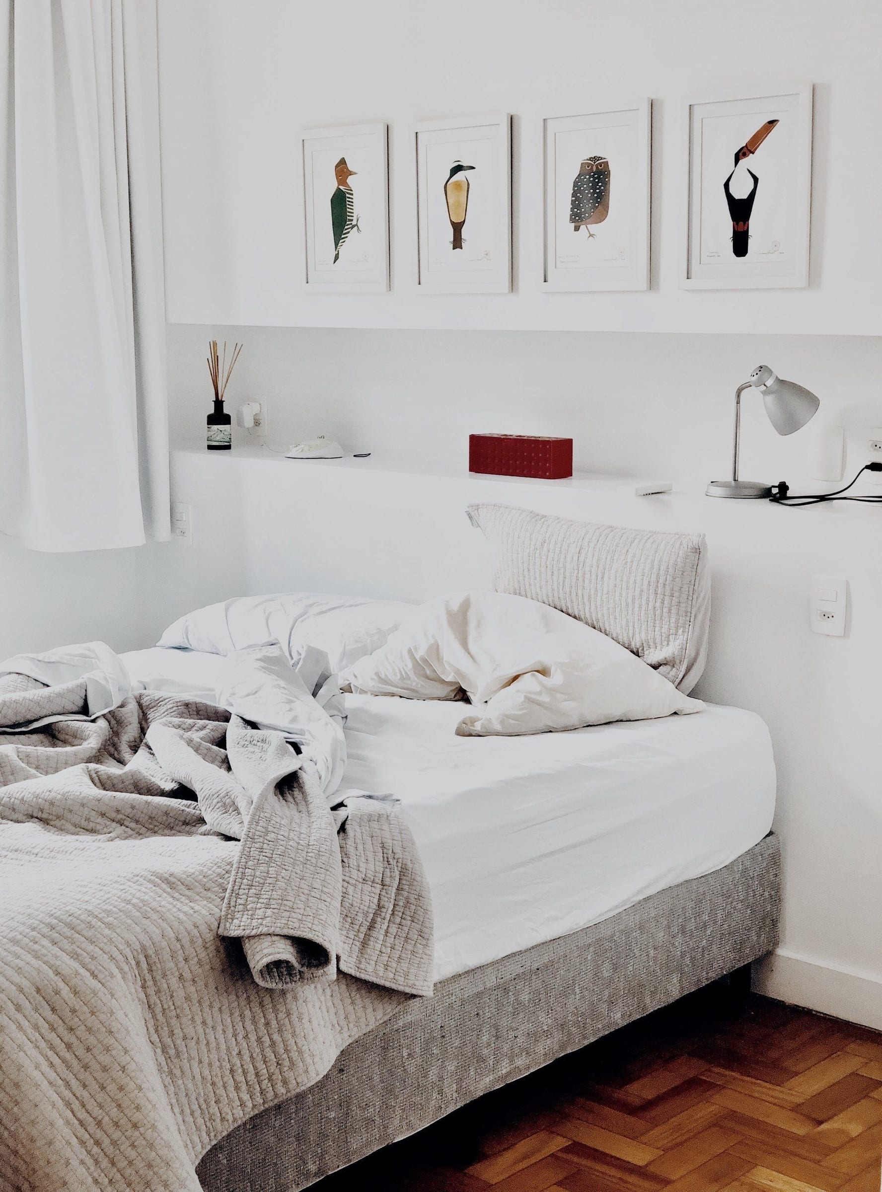 Unmade bed with rumpled bedding, where bed bugs hide in mattress seams and folds